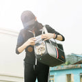 Woman carrying a cat in a breathable pet carrier backpack, perfect for comfort and safety on outdoor adventures.