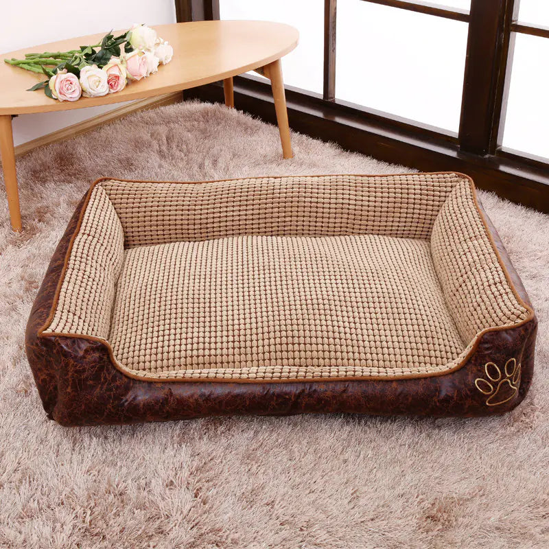 Comfortable removable washable pet bed with brown suede edges on a carpeted floor next to a wooden table with flowers.
