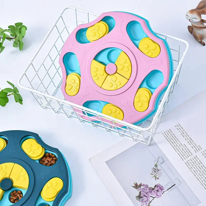 Interactive dog puzzle bowl in pink and blue design for slow feeding, placed in a wire basket on a white surface.