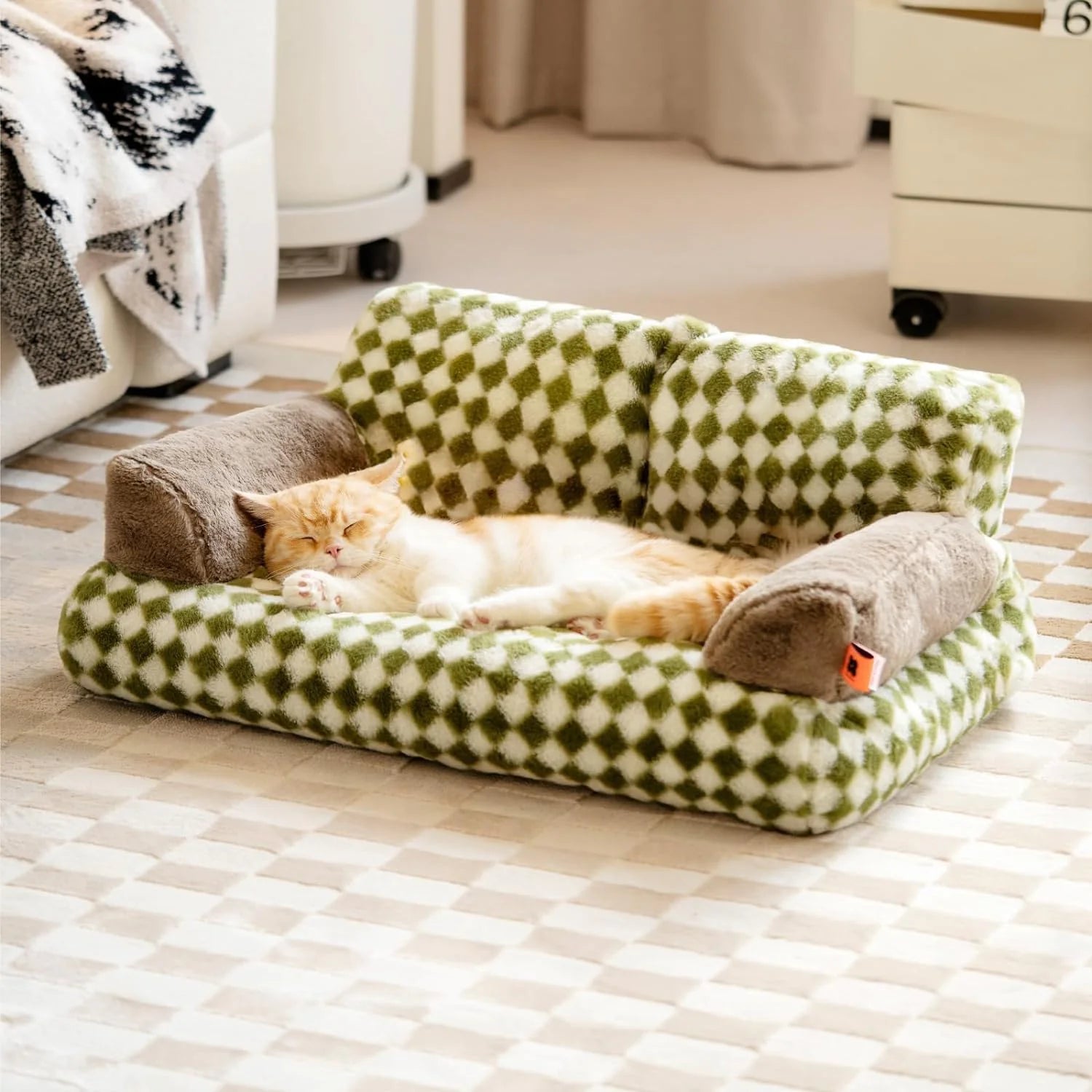 Cat sleeping on a green and white checkered washable fluffy pet couch bed with non-slip design in a cozy room setting.